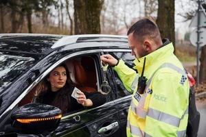 maschio polizia ufficiale nel verde uniforme e con manette rifiuto per prendere corrompere a partire dal donna nel veicolo foto