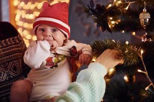 padre e madre con loro bambino decorazione albero insieme nel camera foto