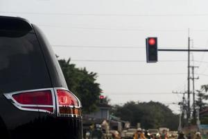 posteriore lato di nero auto con girare su freno luce. fermare su il strada di traffico leggero controllo rosso colore. ambiente di sera volta. sfocato di macchine e le moto parcheggiata foderato su nel il distanza. foto