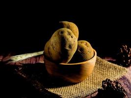 mucchio di crudo patate su buio di legno sfondo. preparazione di Patata la minestra o piatto, Perfetto per pubblicità opuscolo sfondo foto