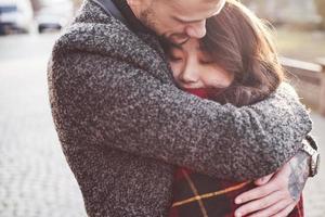 riscaldamento di utilizzando rosso plaid. contento multirazziale coppia insieme all'aperto nel il città. asiatico ragazza con sua caucasico fidanzato foto