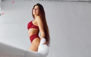 donna nel rosso biancheria intima copertura sua corpo di asciugamano nel il studio contro bianca sfondo foto