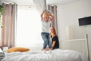 madre giocando e avere divertimento con sua figlio nel Camera da letto a giorno foto