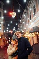 positivo giovane coppia nel caldo Abiti Abbracciare una persona ogni altro su Natale decorato strada foto