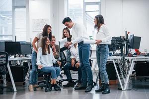 gruppo di giovane attività commerciale persone quello in piedi e seduta e Lavorando nel il ufficio foto