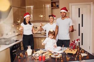 allegro famiglia con sparklers nel mani festeggiare nuovo anno insieme su il cucina foto