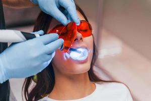 bellissimo donna nel rosso protettivo bicchieri avere un' visitare nel il dentista clinica. concezione di stomatologia foto