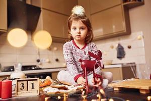 carino poco ragazza seduta e avere divertimento su il cucina con cibo foto