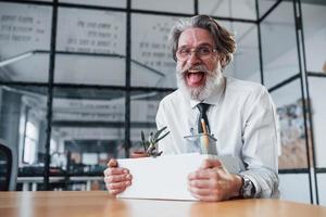 Tenere scatola con Strumenti. maturo uomo d'affari con grigio capelli e barba nel formale Abiti è nel il ufficio foto