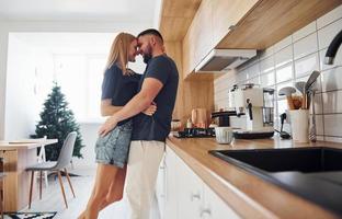 giovane coppia baci ogni altro nel il cucina a mattina tempo foto