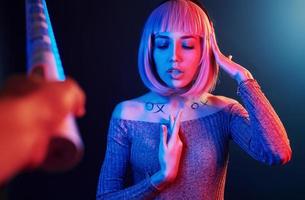 ritratto di giovane ragazza con biondo capelli nel rosso e blu neon nel studio foto