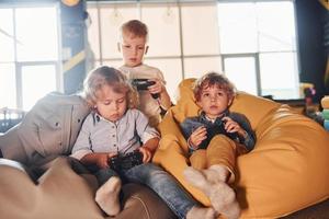 bambini nel casuale Abiti seduta insieme con controllore e giocando video Giochi foto