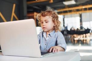 inteligente bambino nel casuale Abiti utilizzando il computer portatile per formazione scolastica scopi o divertimento foto