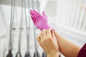 vicino su Visualizza di femmina dentista nel uniforme indossare guanti nel stomatologia ufficio foto