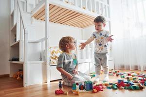 Due poco ragazzi avere divertimento in casa nel il Camera da letto con plastica costruzione impostato foto