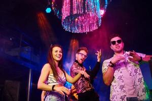 giovane persone è avendo divertimento nel notte club con colorato laser luci foto
