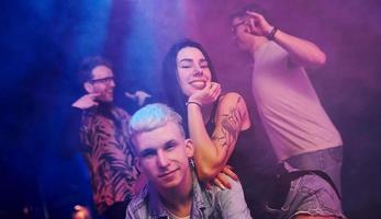 andando pazzo e in posa per il telecamera insieme. giovane persone è avendo divertimento nel notte club con colorato laser luci foto