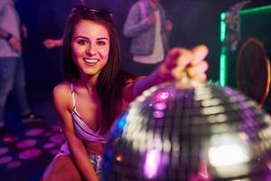 ragazza seduta dentro di notte club con festa palla nel mani foto