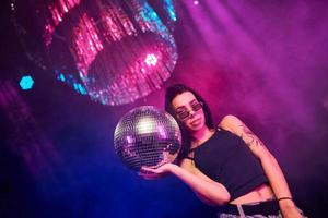 bellissimo giovane ragazza avere divertimento, danza nel il notte club. Tenere festa palla foto