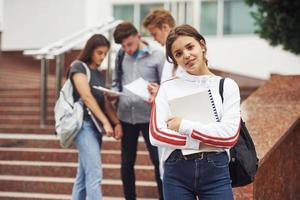 carino adolescente ragazza. gruppo di giovane studenti nel casuale Abiti vicino Università a giorno foto