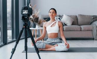 blogger giovane donna con sottile corpo forma nel abbigliamento sportivo fare yoga in casa a casa foto
