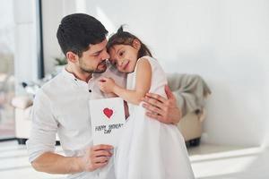 contento Il padre di giorno. figlia fa sorpresa per papà di dando cartolina con cuore foto