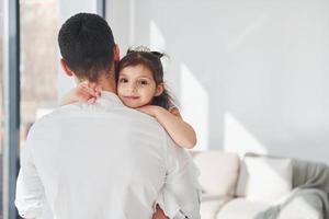 contento padre con il suo figlia Abbracciare una persona ogni altro a casa foto