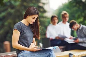 Lavorando a progetto. gruppo di giovane studenti nel casuale Abiti nel il città a giorno foto