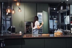 preparazione fresco cibo. giovane bellissimo brunetta nel casuale Abiti in casa nel cucina a giorno foto