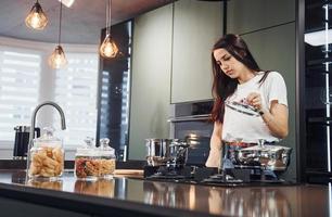 preparazione fresco cibo. giovane bellissimo brunetta nel casuale Abiti in casa nel cucina a giorno foto