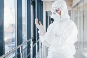 femmina medico scienziato nel laboratorio cappotto, difensiva occhiali e maschera in piedi in casa e indossare guanti foto