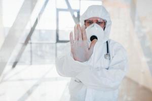 fermare il virus gesto. femmina medico scienziato nel laboratorio cappotto, difensiva occhiali e maschera in piedi in casa foto