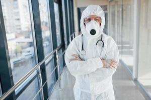 femmina medico scienziato nel laboratorio cappotto, difensiva occhiali e maschera in piedi in casa foto