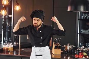 ritratto di professionale giovane capocuoco cucinare nel uniforme quello in posa per telecamera su il cucina foto