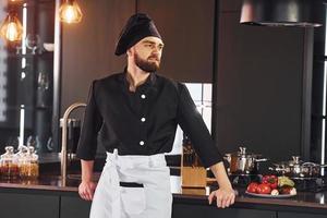 ritratto di professionale giovane capocuoco cucinare nel uniforme quello in posa per telecamera su il cucina foto