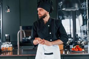 ritratto di professionale giovane capocuoco cucinare nel uniforme quello in posa per telecamera su il cucina foto