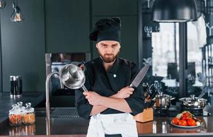 ritratto di professionale giovane capocuoco cucinare nel uniforme quello in posa per telecamera su il cucina foto