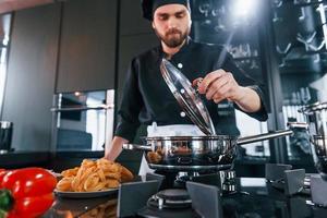 professionale giovane capocuoco cucinare nel uniforme Lavorando su il cucina foto