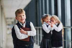 bambino prende vittima di bullismo. concezione di molestie. scuola bambini nel uniforme insieme nel corridoio foto