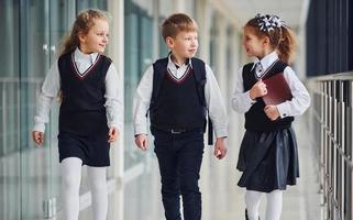 scuola bambini nel uniforme insieme nel corridoio. concezione di formazione scolastica foto