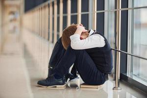 ragazzo nel uniforme seduta solo con sensazione triste a scuola. concezione di molestia foto