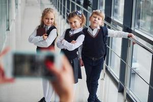 scuola bambini nel uniforme fabbricazione un' foto insieme nel corridoio. concezione di formazione scolastica
