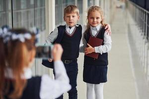 scuola bambini nel uniforme fabbricazione un' foto insieme nel corridoio. concezione di formazione scolastica