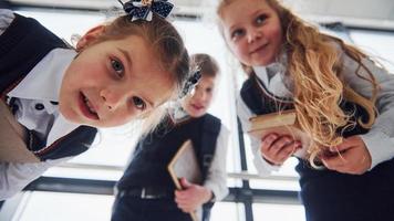 scuola bambini nel uniforme in posa per un' telecamera insieme nel corridoio. concezione di formazione scolastica foto