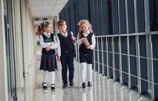 scuola bambini nel uniforme con libri insieme nel corridoio. concezione di formazione scolastica foto