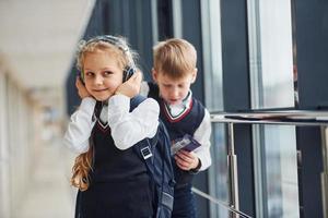 poco ragazza con cuffie nel uniforme quello insieme con ragazzo nel corridoio. concezione di formazione scolastica foto