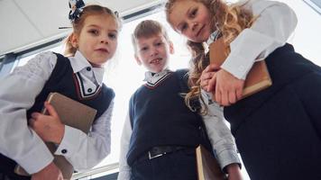 scuola bambini nel uniforme in posa per un' telecamera insieme nel corridoio. concezione di formazione scolastica foto