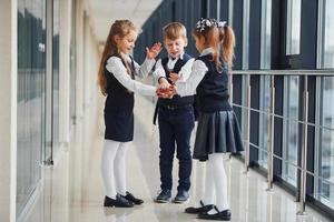 scuola bambini nel uniforme fabbricazione vittoria gesto insieme nel corridoio. concezione di formazione scolastica foto