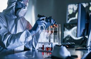 scienziato nel bianca protettivo uniforme lavori con coronavirus e sangue tubi nel laboratorio foto