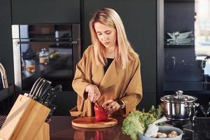 bellissimo bionda in piedi in casa nel cucina e preparazione cibo foto